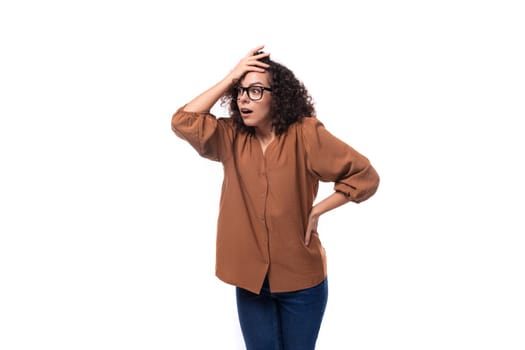 young surprised european curly woman with curled hair on a curling iron is dressed in a brown shirt.