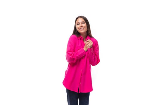 positive inspired young brunette lady dressed in a bright pink shirt and jeans on a white background.