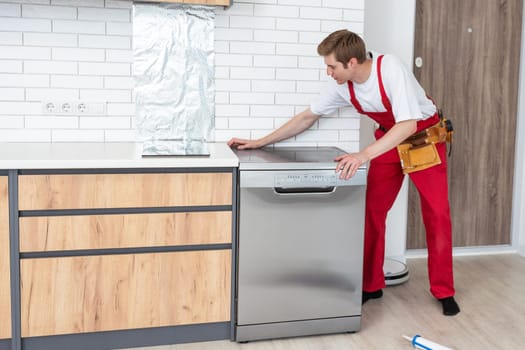 Full length of repairman repairing dishwasher with screwdriver in kitchen