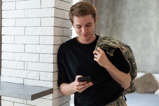 Young army man using smartphone at home.