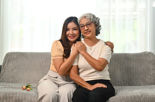 Image of happy young woman embracing happy senior mother and smiling at camera.