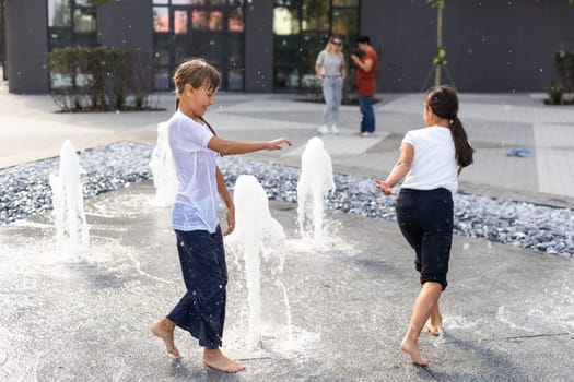 On a hot day, children run and have fun at the city fountain. Leisure time concept. summer holidays. happy childhood. High quality photo