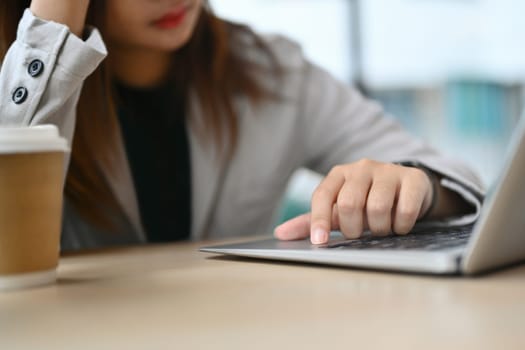 Frustrated businesswoman touching her head using laptop computer at office desk.