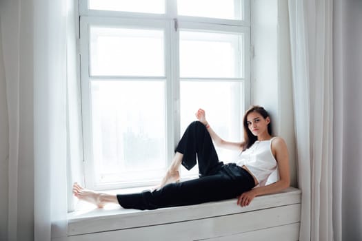 Portrait of a beautiful woman at the window in a white room