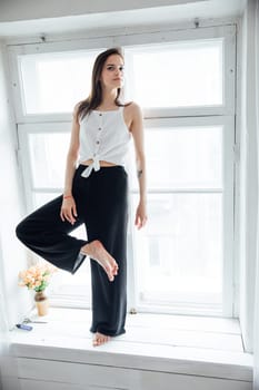 Portrait of a beautiful woman at the window in a white room