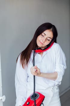 woman talking on vintage red wired phone