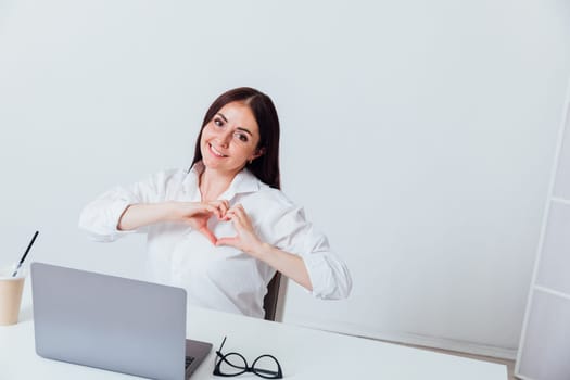 woman working online at computer showing hands heart