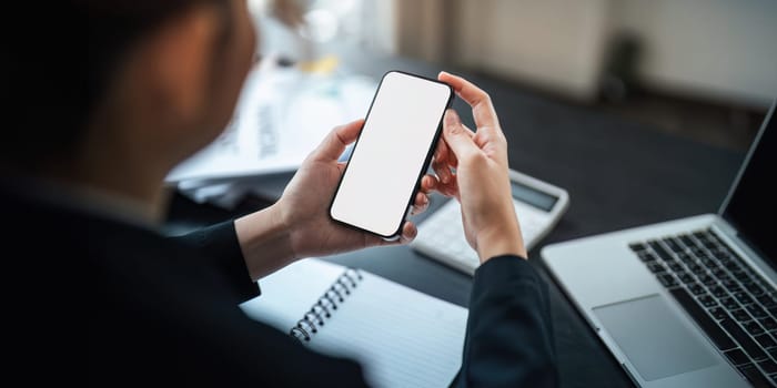 Business woman hand holding using mockup mobile phone with white blank screen for text, mobile app design and advertising, online marketing.