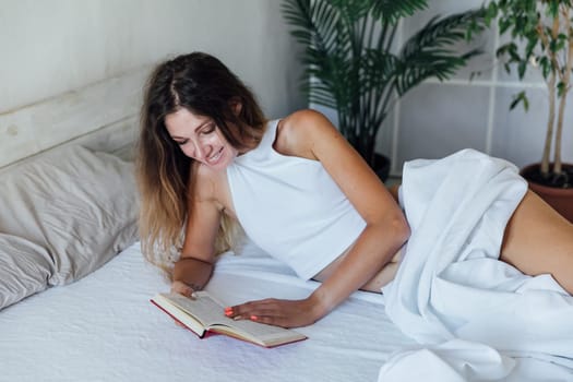 woman reading a book in the bedroom on the bed