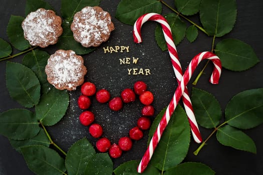 inscription of new year on a black board with cupcakes and candy red.
