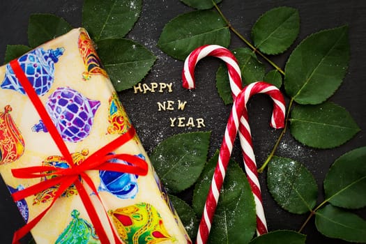 inscription of new year on a black board with gift and red candy.