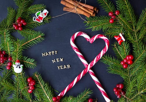 Christmas tree with ornaments and candy on a black background. The inscription Happy New Year.