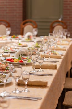 Served festive table with snacks, glasses, glasses, cutlery and napkins for a banquet on the occasion of a wedding or birthday or Christmas or other bright event in the restaurant