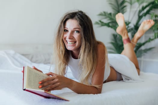 Cute lovely woman reading book and drinking coffee on bed