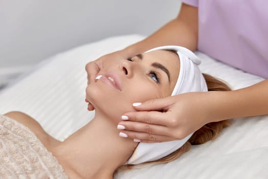 Beautiful woman getting face massage treatment in beauty salon. Skin care.