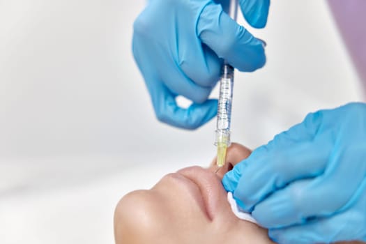 cosmetologist makes injections to enlarge the lips of beautiful woman. lip shape correction