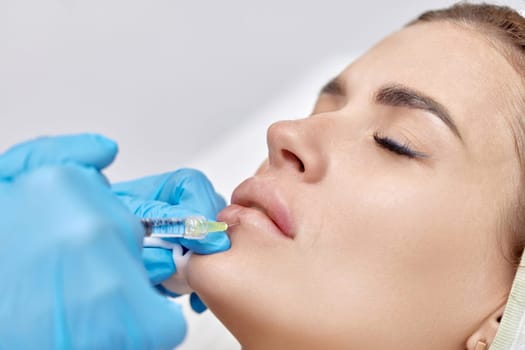 cosmetologist makes injections to enlarge the lips of beautiful woman. Lips filler injection
