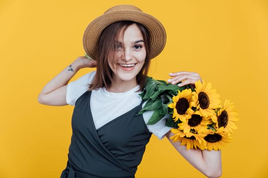 Portrait of a young woman with sunflower flowers on a yellow background