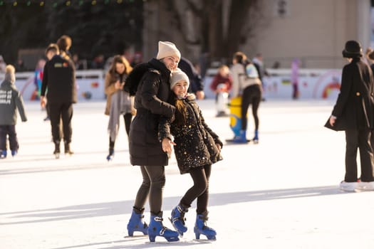 Adorable young mother with her daughter on the ice rink.