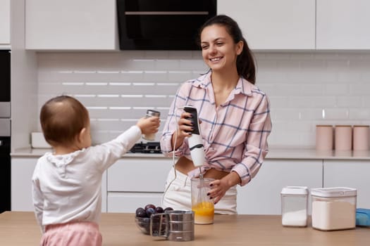 happy mother with her little daughter cooking at white kitchen. baking together