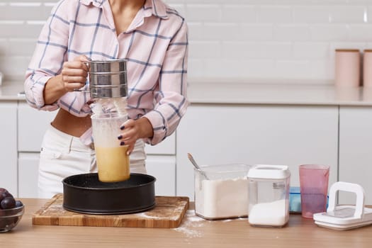 housewife woman sifting flour, female hands preparing pie in modern kitchen