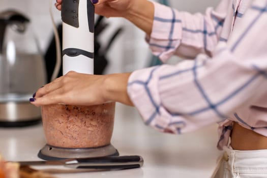 woman using blender and grinding meat. Preparation of minced meat.