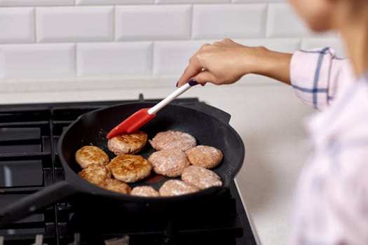 Woman preparing meat cutlets in white kitchen