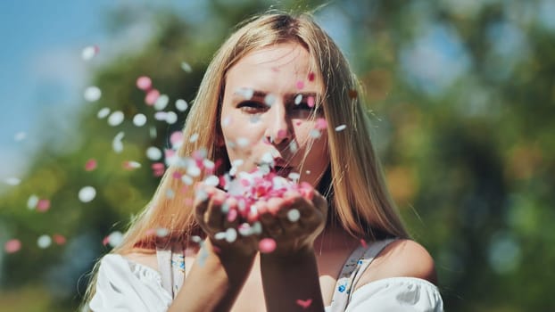 The girl blows colorful paper confetti out of her hands