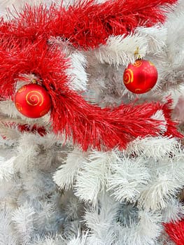 Red baubles with golden ornament on white pine tree brenches. Closeup look of Christmas decorations