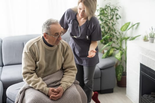 Kind female doctor embracing encouraging senior male patient in hospital. Happy healthy older man and his physician enjoying talking at nursing home. Elderly medical health care concept