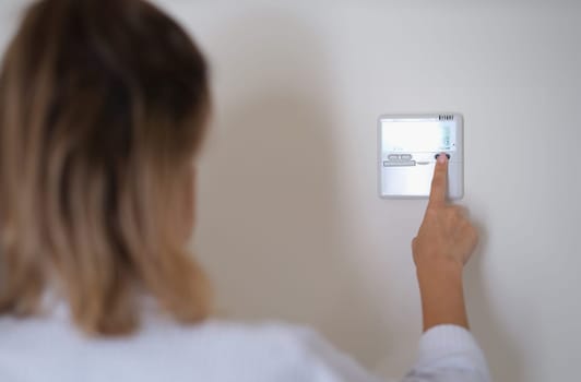 Woman pressing button on remote control of air conditioner in wall closeup. Comfortable temperature at home concept