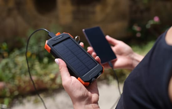 Mobile phone and solar power bank in hands closeup. Modern energy saving devices for recharging devices concept