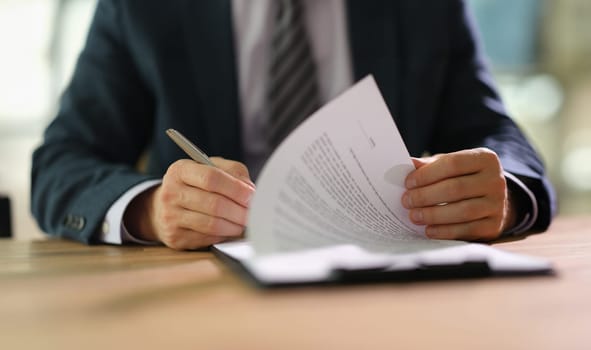 Businessman leafing through documents and signing contract for business deal at work in office closeup. Certification of documentation and control concept