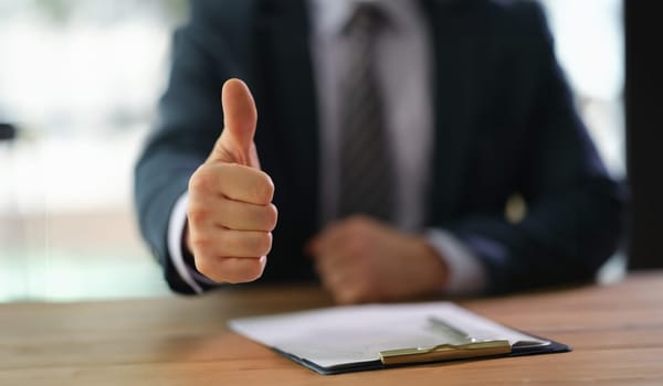 Businessman showing thumb up at work in office closeup. successful business people concept