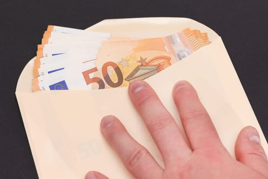 Hand Holds An Orange Paper Envelope with Stack of 50-Euro Banknotes Inside. Salary in Cash. Tax-Free System. Euro Currency. Payments with No Taxes. Orange Paper Money. A Lot of Fifty-Euro Bills
