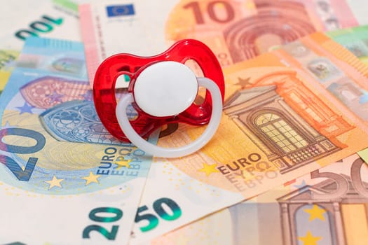 Childfree, Contraception and Birth Control Concept: Baby Pacifier on the Euro Banknotes. Having Children is Expensive and Unprofitable