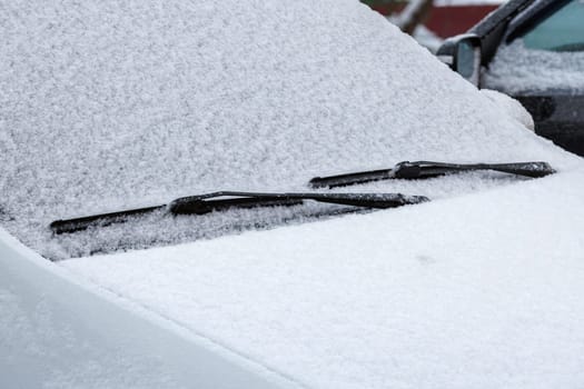 snow covered car windshield, wipers and bonnet - closeup full-frame view under daylight