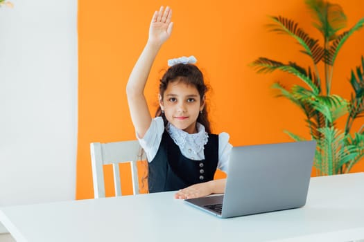 School girl sitting at desk with laptop at lesson at school