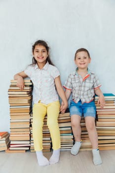 Boy and girl sitting on stacks of books