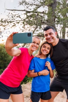 happy sporty family taking a selfie photo in the nature with mobile phone, concept of outdoor activities with children and healthy lifestyle, copy space for text