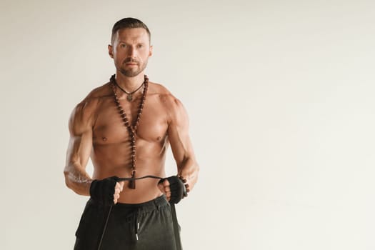 A man with a naked torso is engaged in strength fitness using a rubber loop indoors.