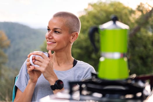 smiling woman having a coffee in the countryside, concept of active tourism in nature and outdoor activities