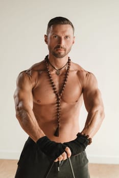 A man with a naked torso is engaged in strength fitness using a rubber loop indoors.