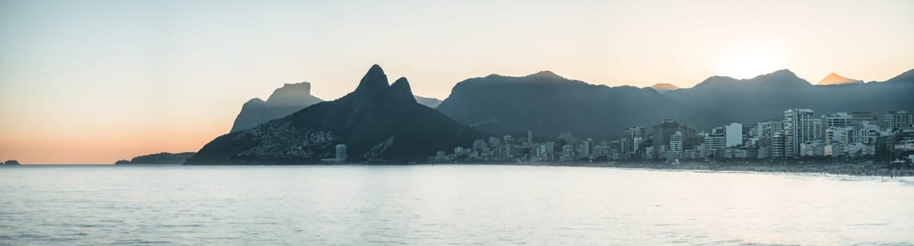 Stunning sunset at Ipanema Beach with views of Two Brothers mountain and Pedra da Gavea as Rio city lights come to life.