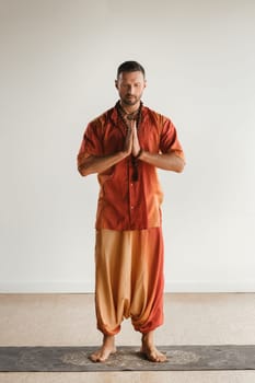 a man in an orange suit does yoga in a fitness room. The concept of health.