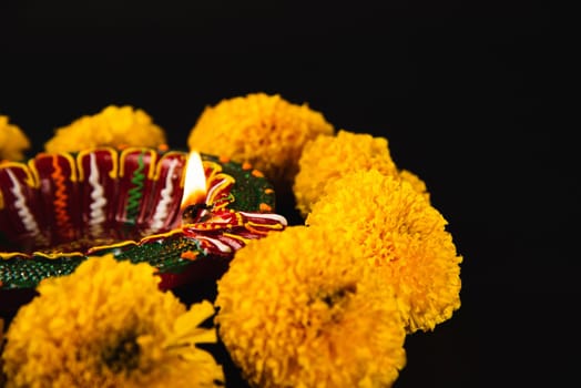 Intricate Diwali lamp and colorful flower rangoli illuminate a captivating black background. Ideal for Diwali, weddings, and cultural celebrations.