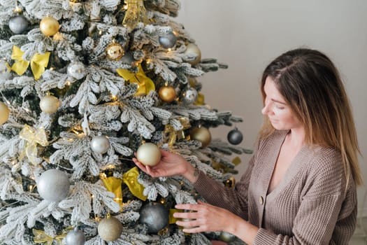 woman decorating christmas tree with gifts and toys