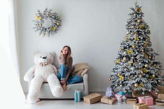 woman decorating christmas tree with gifts and toys