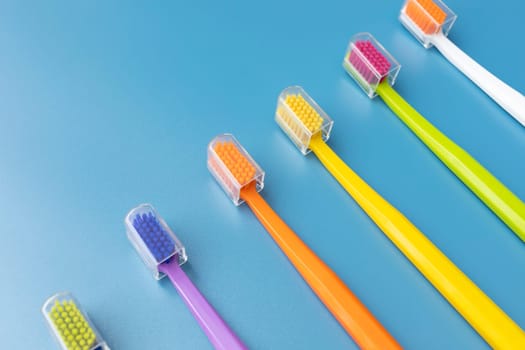 Top View Many Colorful Antibacterial Toothbrushes on Blue Background. Flat Lay Set for Dental Hygiene, Bathing Self Care Products. Horizontal Plane High quality photo