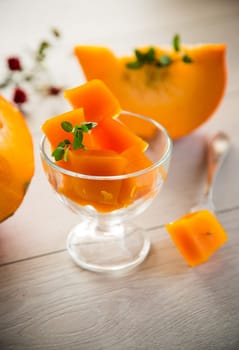 Prepared sweet pumpkin marmalade in a glass bowl on a wooden table. Autumn recipes.